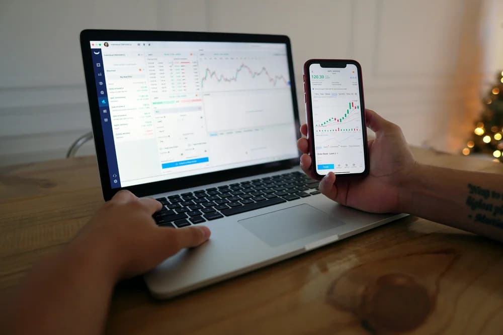 Laptop and phone showing financial trading dashboards